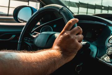 Hands of the driver on the steering wheel inside the car