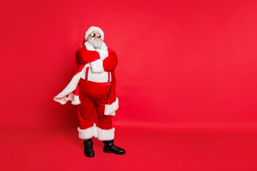 Full length photo of minded fat overweight santa claus bad guy with his hands crossed big abdomen choose naughty kids wear eyeglasses isolated over red background