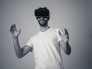 Portrait of excited and amazed young man wearing Virtual Reality headset exploring 3D world