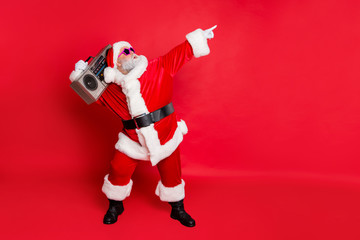 Full length profile side photo of funny santa claus raise his arms dance wear stylish trendy eyewear eyeglasses hat headwear isolated over red background