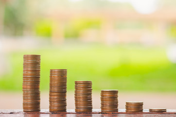 coin stacking on wood table with green nature background. money saving and financial banking concept for investment.