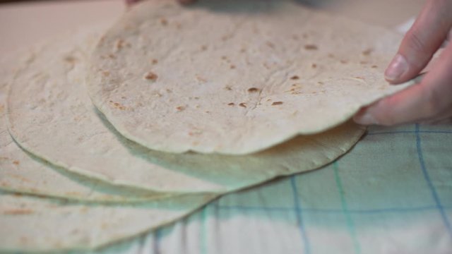 Woman put a fresh organic Italian piadina romagnola pizza tortilla bun on a tablecloth. Food.