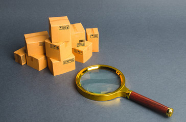 A pile of boxes and a magnifying glass. Concept search for goods and services. Tracking parcels via...