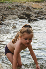 Little cute beautiful girl swims in a mountain river.