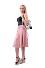 Side view of sexy smart blonde woman in stylish clothes with glasses and silver bag on shoulder. Full body isolated on white background.