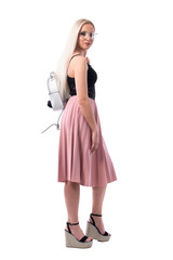 Side view of blonde young stylish fashionable woman with glasses and bag turning and leaving. Full body isolated on white background.