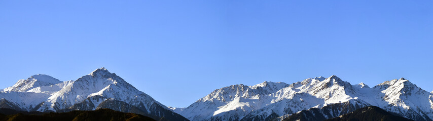 Fototapeta na wymiar Panorama of mountain peaks with freshly fallen white snow.