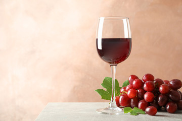 Grape and glass with wine on grey background, space for text