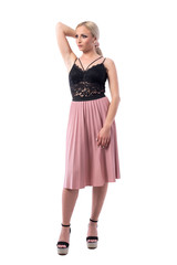 Beautiful confident blonde woman fashion model holding hair in pink skirt looking away. Full body isolated on white background.