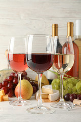 Fruits, cheese, bottles and glasses with different wine on white background, space for text