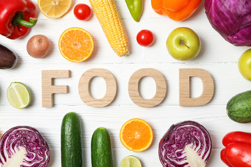 Word Food laid out of wooden letters, vegetables and fruits on wood background, top view