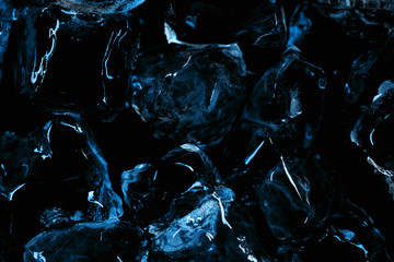 frozen transparent ice cubes with blue lighting isolated on black