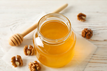 Walnuts, dipper, parchment and glass jar with honey on white background, closeup