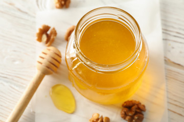 Walnuts, dipper, parchment and glass jar with honey on white background, closeup