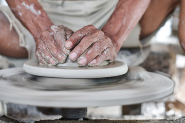 Close up of professional potter's hand working on pottery wheel.