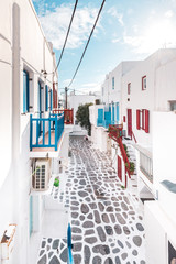 Typical Greek architecture in the white, cobbled alleys of Mykonos town, houses in the old town of Chora with colorful balconies and white churches, Cyclades, Greece - obrazy, fototapety, plakaty