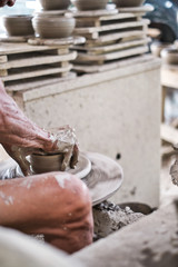 Close up of professional potter's hand working on pottery wheel.