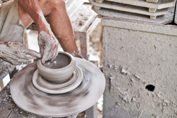 Close up of professional potter's hand working on pottery wheel.