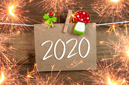 Chalkboard with four leaf clover and chimney sweeper and sparklers with happy new year 2020 on wooden background