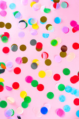 Colorful confetti on pink pastel trendy background. Festive backdrop for your projects.
