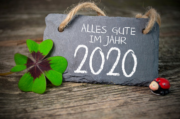 Chalkboard with four leaf clover and chimney sweeper and sparklers with happy new year 2020 on...