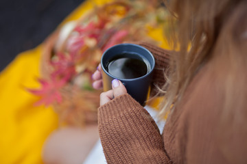 Outdoors autumn picnic. Woman holding mug of hot coffee in a hand