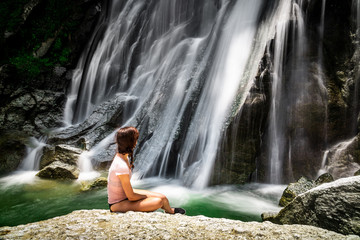 Young woman at a waterfall. Low shutterspeed with silky smooth water. Shot at Hoang Su Phi, Ha Giang province, Vietnam. 