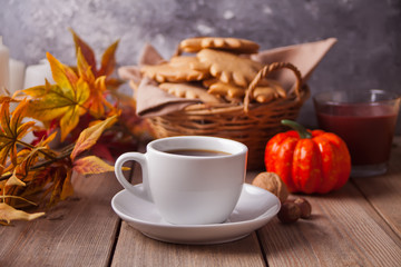 Cup of coffee, autumn leaves, cookies, pumpkin on the wooden table. Autumn harvest. Autumn concept.