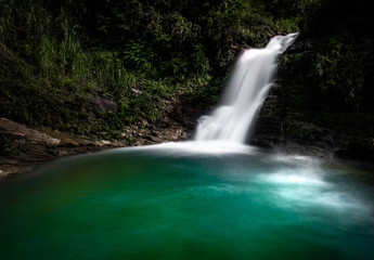 Obraz premium Emerald green waterfall at Du Gia, at the Ha Giang loop in Northern Vietnam. Stunning landscape long exposure photo. 