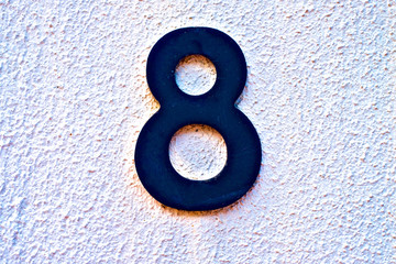 Eight, number 8, black digit on pastel wall.