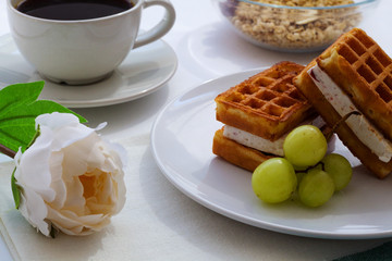 Breakfast. Belgian waffles and cup of black coffee with oat-flakes on white background.