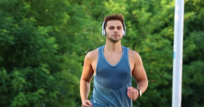 Young man with headphones running in park