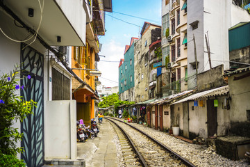 Fototapeta na wymiar Perspective view of Hanoi city railway running along narrow street with houses in Vietnam