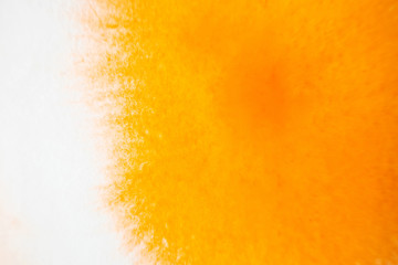A stain of orange watercolor paint on paper dipped in water. Macro photo. Background minimalistic vibrant image. The concept of drawing.