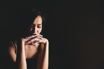 Sad depressed woman suffering from family life. women sitting in dark room and touching her face feeling worry. Young beautiful women thinking how to solve problem.