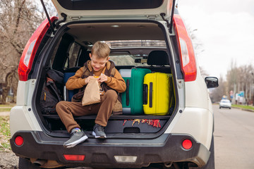 little kid looking into paper bag with candies sitting in car trunk