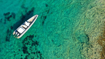 Aerial top view luxury inflatable rib speed boat docked in mediterranean emerald bay with crystal clear sea