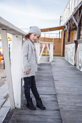 Fototapeta premium A fashionable little girl in a knitwear by the sea in the fall
