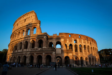 Fototapeta na wymiar Tourists visiting the famous Colosseum under the beautiful light of the golden hour in Rome