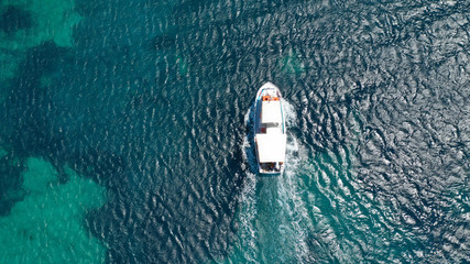 Aerial bird's eye view photo taken by drone of boat cruising in Caribbean tropical beach with turquoise - sapphire waters