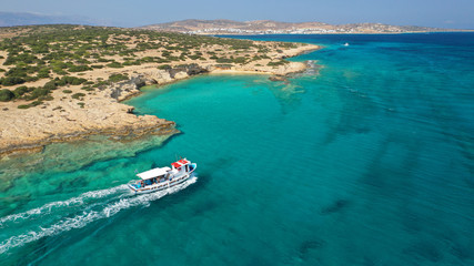 Obraz premium Aerial drone photo of picturesque and traditional tourist vessel cruising in famous beaches of Koufonisi island, Small Cyclades, Greece