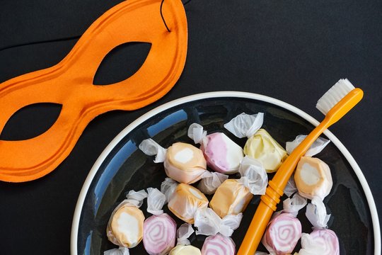 Colorful Halloween sweets with mask and toothbrush, dentist’s message concept