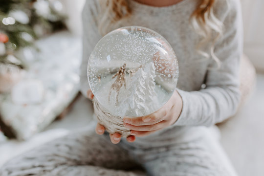 Girl sitting on the floor holding a snow globe at Christmas