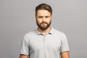 Happy young man. Portrait of handsome young man in casual smiling while standing against grey background