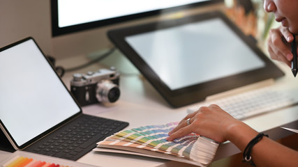 Cropped graphic designer man selected colour guide on creative workspace.