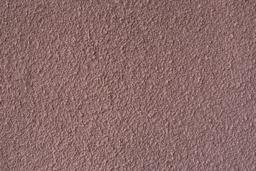 Background texture of the facade of a concrete wall with stucco light burgundy