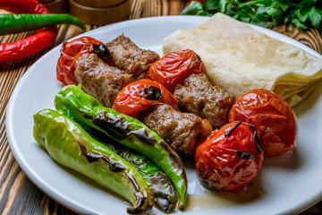 Lula kebab with tomatoes on wooden table Turkish cuisine