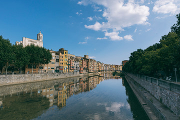 Girona city skyline with river houses colourful facades reflected on quiet river water on a blue summer sunny sky