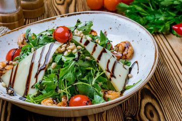 Arugula with shrimps and tomatoes on wooden table