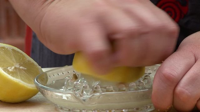 Handheld, close up shot of a lemon being twisted on a juicer.